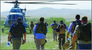 Image of several people with backpacks walking towards a helicopter.